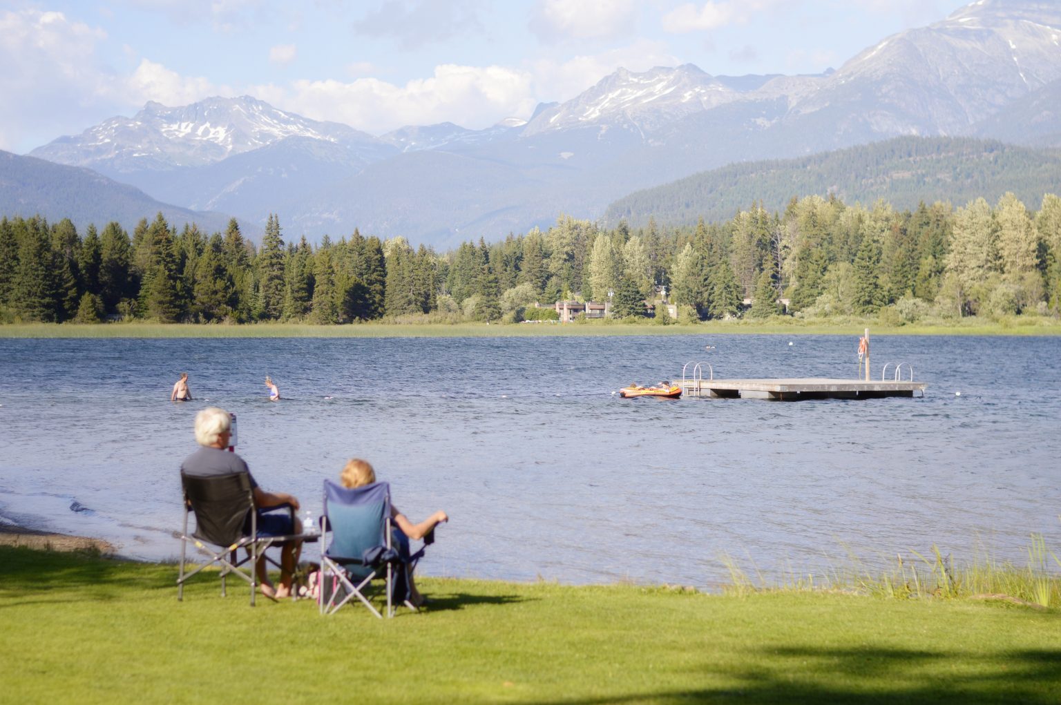a man and woman sitting on chairs by a lake