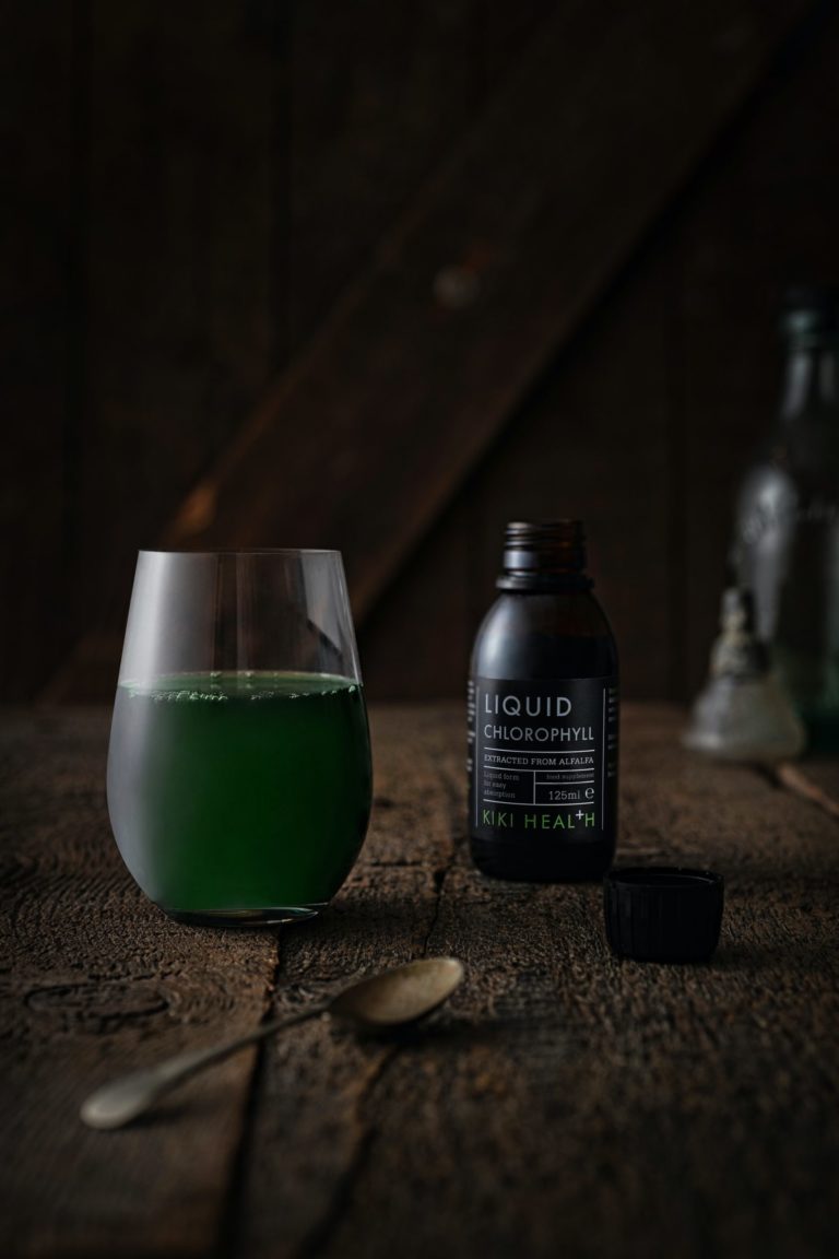 a glass of green liquid next to a bottle of green liquid