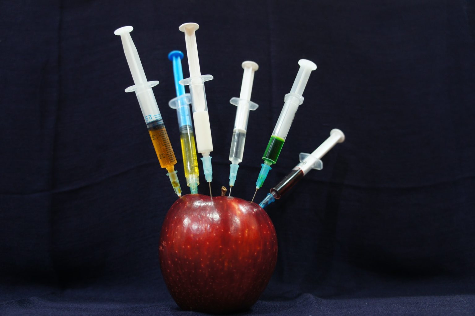 a few toothbrushes sit on top of an apple