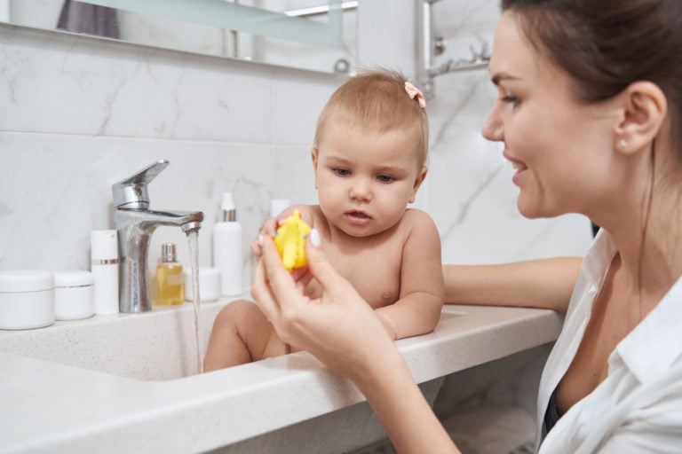 a person holding a baby in a sink