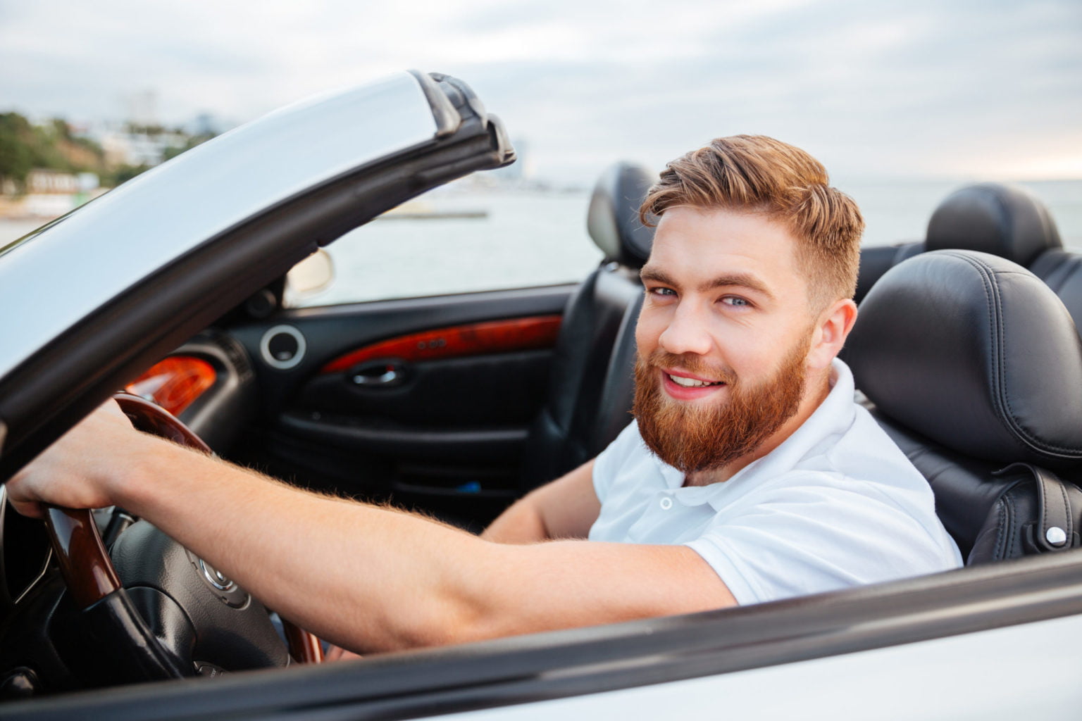 Portrait of young handsome smiling man in his own car